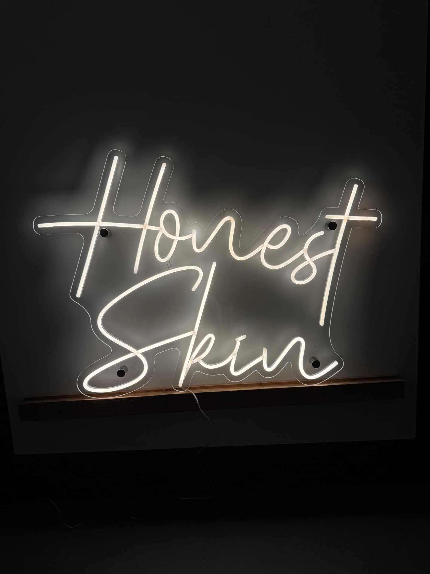 Honest Skin custom white script sign on a dark wall